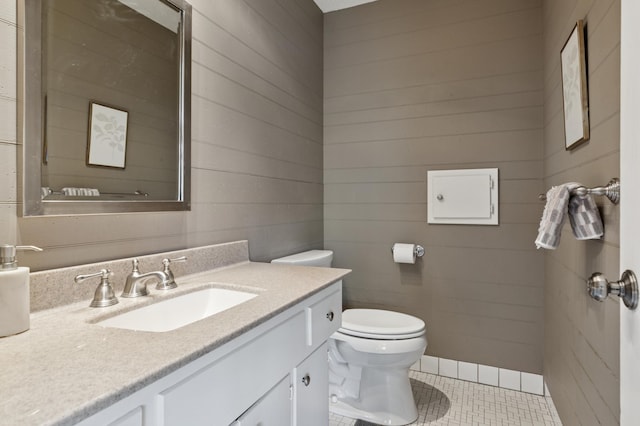 bathroom with toilet, vanity, tile patterned flooring, and wooden walls
