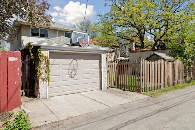 garage featuring concrete driveway and fence