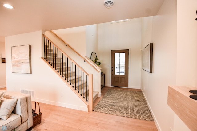 foyer entrance featuring visible vents, stairs, wood finished floors, baseboards, and recessed lighting