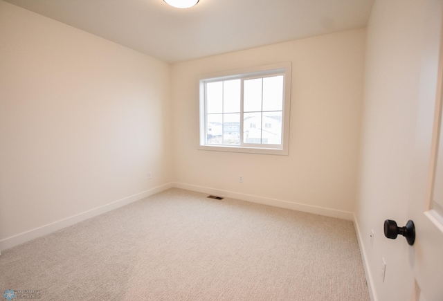 spare room with baseboards, light colored carpet, and visible vents