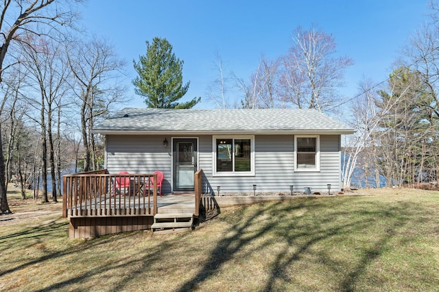 view of front of home featuring a wooden deck, roof with shingles, and a front lawn