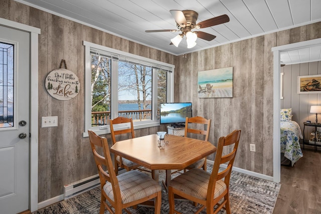 dining space featuring crown molding, ceiling fan, baseboard heating, baseboards, and wood finished floors