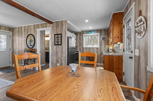 dining space featuring beamed ceiling, baseboards, wallpapered walls, wooden ceiling, and light wood finished floors