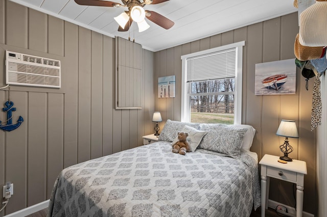 bedroom with an AC wall unit, a ceiling fan, and a decorative wall