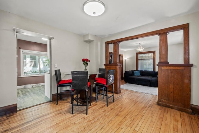 dining space featuring light wood finished floors, plenty of natural light, a chandelier, and baseboards