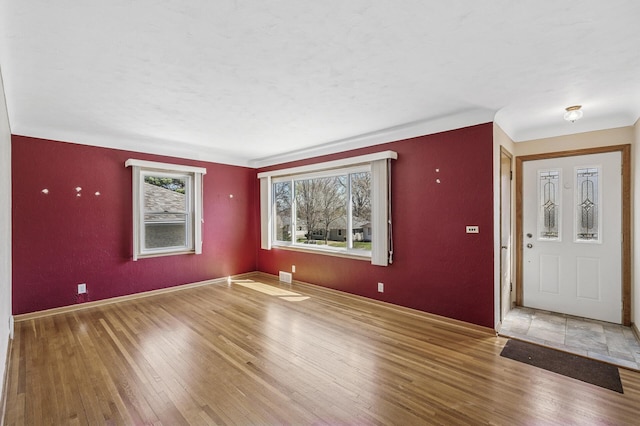 entrance foyer with baseboards, wood finished floors, and visible vents