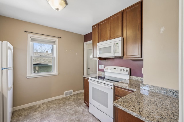 kitchen with visible vents, brown cabinetry, baseboards, and white appliances