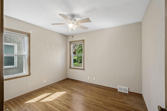 unfurnished room featuring baseboards, ceiling fan, visible vents, and wood finished floors