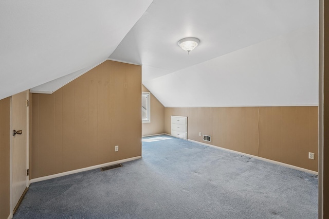 additional living space with visible vents, carpet, baseboards, and vaulted ceiling