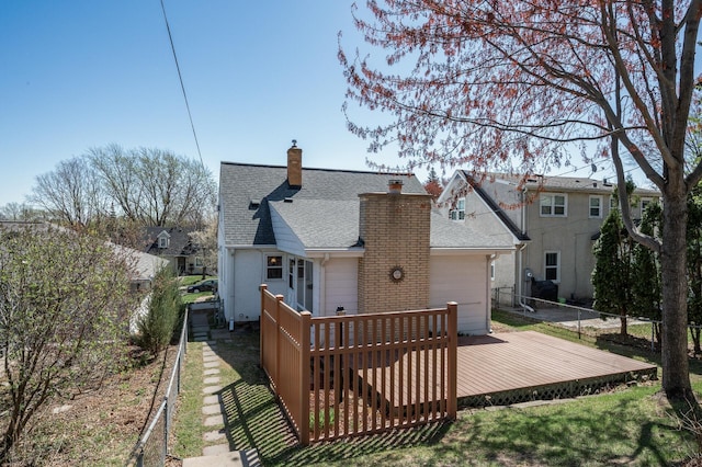 back of house with a shingled roof, fence, a chimney, and a deck