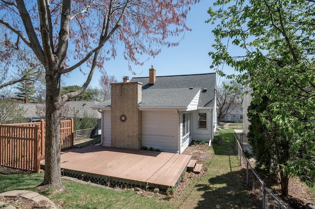 rear view of house featuring fence, roof with shingles, a chimney, and a deck
