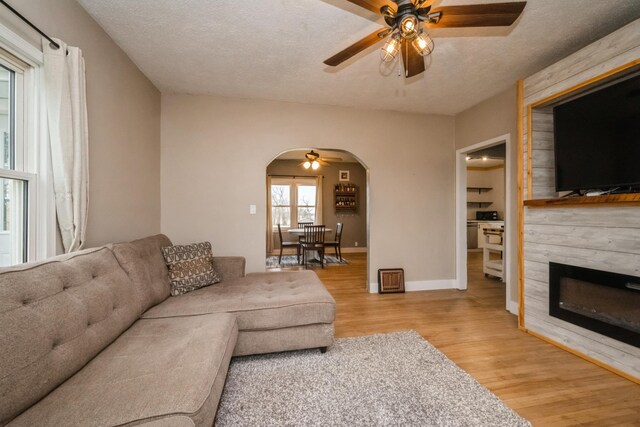 17492 460th Ln, Waterville, MN 56096 - living room featuring wood finished floors, a fireplace, a textured ceiling, ceiling fan, and arched walkways