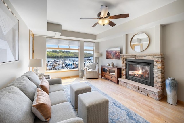 living area with wood finished floors, a fireplace, and a ceiling fan