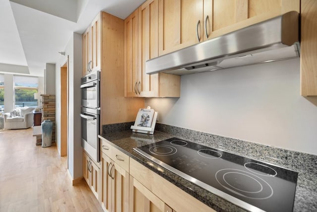kitchen with under cabinet range hood, black electric cooktop, light brown cabinetry, stainless steel double oven, and light wood-style floors