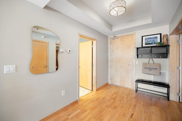 corridor with wood finished floors and a tray ceiling
