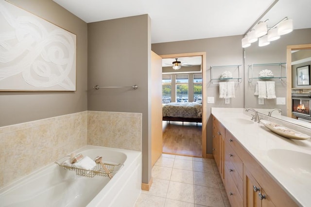 bathroom featuring a ceiling fan, ensuite bathroom, a garden tub, tile patterned floors, and double vanity