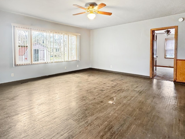 empty room with a ceiling fan, wood finished floors, and baseboards