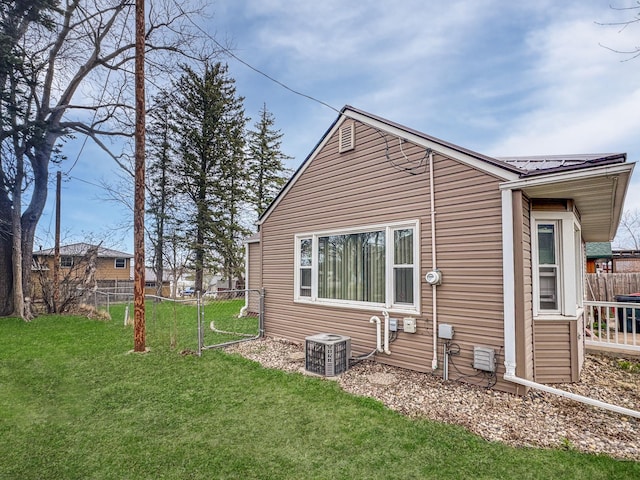 exterior space featuring metal roof, a lawn, central AC, and fence