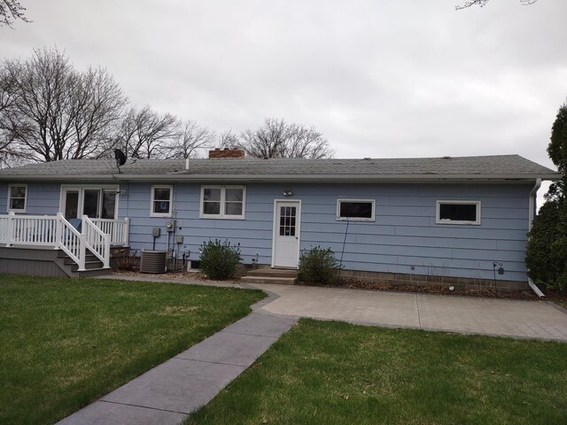 122 10th St, Madison, MN 56256 - back of house with a chimney, a lawn, a wooden deck, and roof with shingles