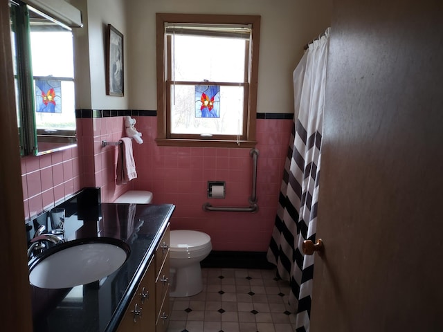 122 10th St, Madison, MN 56256 - full bathroom with plenty of natural light, tile walls, vanity, a wainscoted wall, and toilet