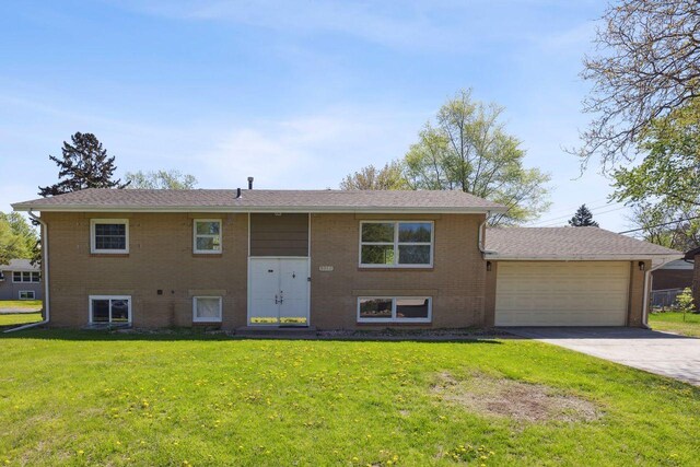 8040 Xenia Ave N, Brooklyn Park, MN 55443 - bi-level home with a garage, brick siding, a front yard, and driveway