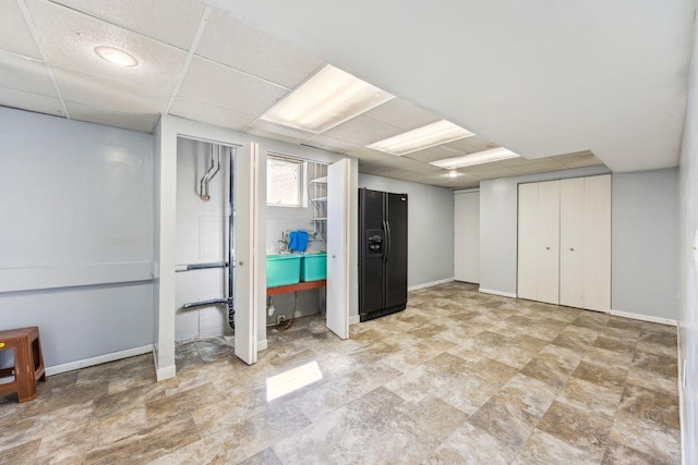 8040 Xenia Ave N, Brooklyn Park, MN 55443 - basement with black fridge with ice dispenser, baseboards, a paneled ceiling, and stone finish floors