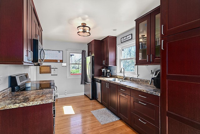 kitchen featuring a sink, stainless steel appliances, light wood-type flooring, and baseboards