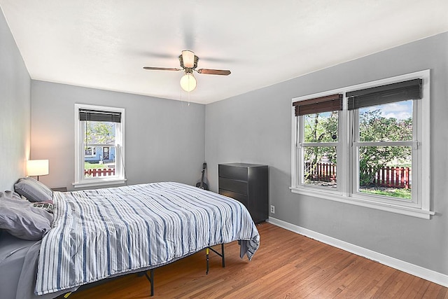bedroom with baseboards, wood-type flooring, and a ceiling fan
