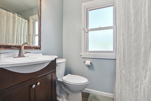 bathroom featuring baseboards, toilet, and vanity