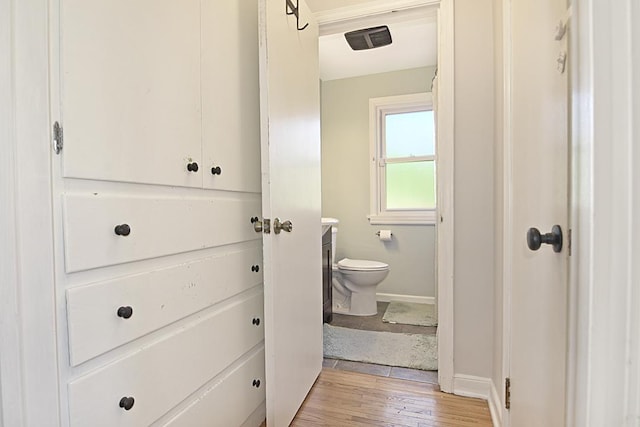 bathroom with toilet, wood finished floors, baseboards, and vanity