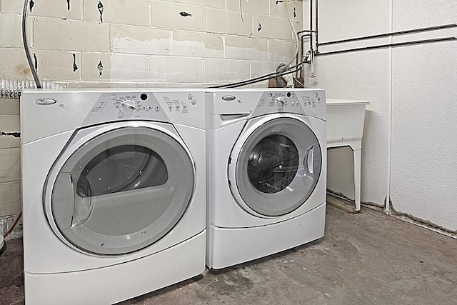 laundry area with washing machine and dryer and concrete block wall