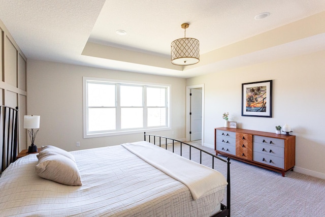bedroom featuring baseboards, a tray ceiling, and light carpet