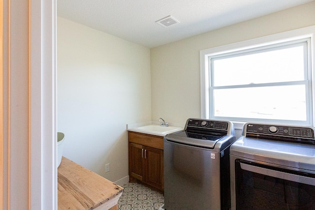 clothes washing area with cabinet space, separate washer and dryer, visible vents, and a sink