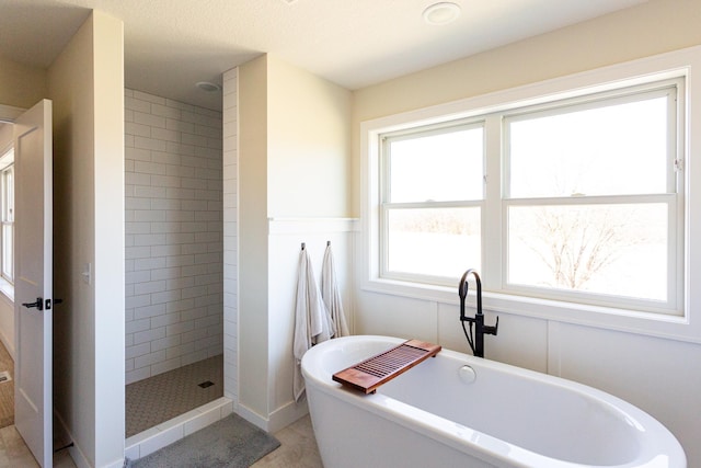 bathroom with a soaking tub and tiled shower