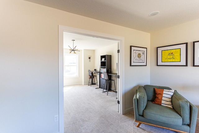 living area featuring an inviting chandelier, baseboards, and carpet