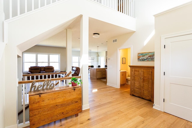 interior space with a towering ceiling, light wood finished floors, and visible vents