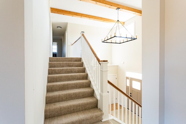 staircase featuring beam ceiling and a chandelier