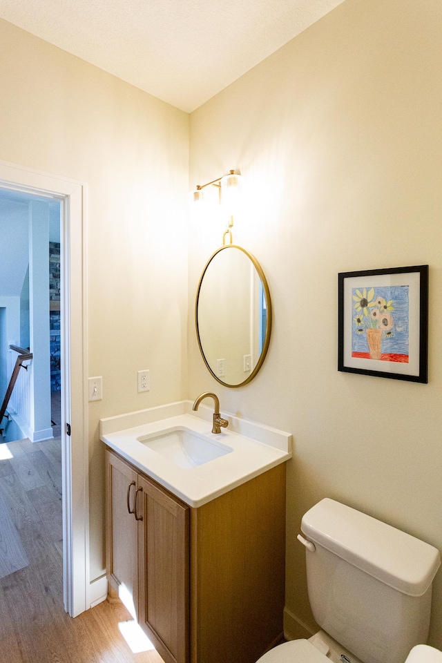 bathroom featuring toilet, wood finished floors, and vanity