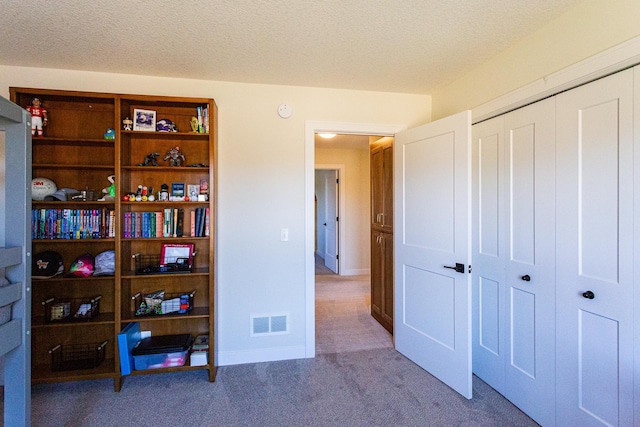 carpeted bedroom featuring a closet, a textured ceiling, and visible vents