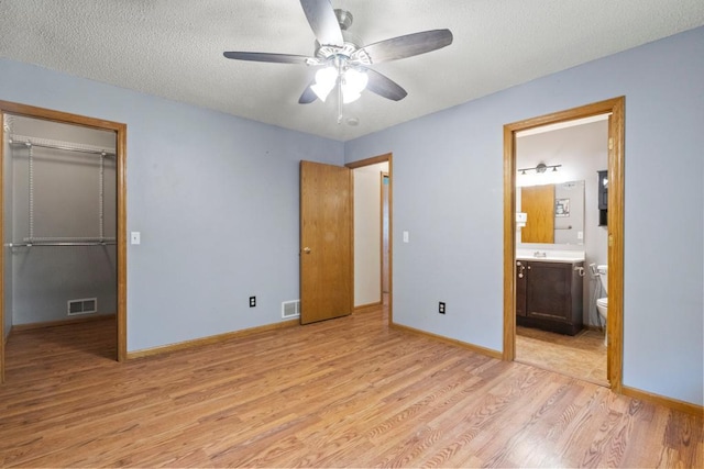 1312 Widgeon Way, Buffalo, MN 55313 - unfurnished bedroom featuring light wood-type flooring, a closet, a textured ceiling, connected bathroom, and ceiling fan