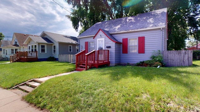 bungalow-style home featuring fence, a wooden deck, a shingled roof, and a front yard