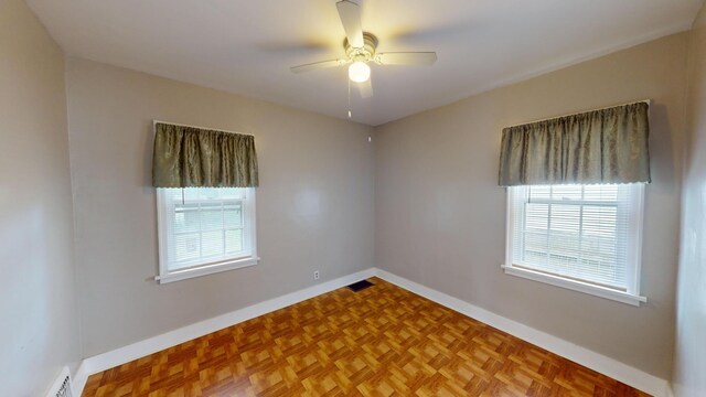 empty room featuring baseboards, ceiling fan, and visible vents