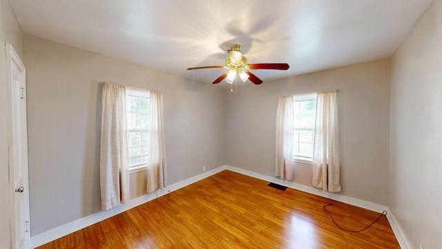 spare room with a ceiling fan, baseboards, visible vents, and light wood-style floors
