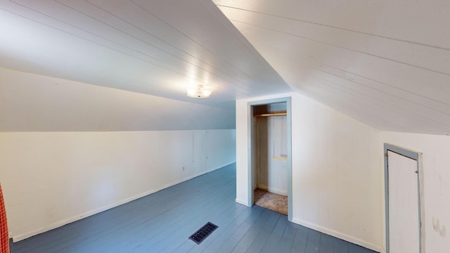 additional living space featuring baseboards, visible vents, lofted ceiling, and dark wood-type flooring