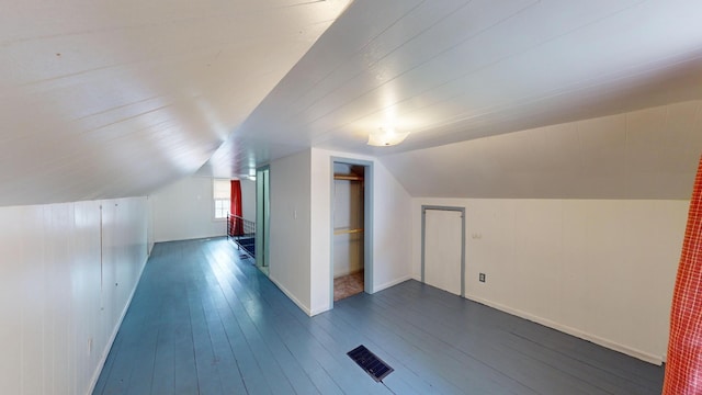 additional living space featuring visible vents, lofted ceiling, and dark wood-type flooring