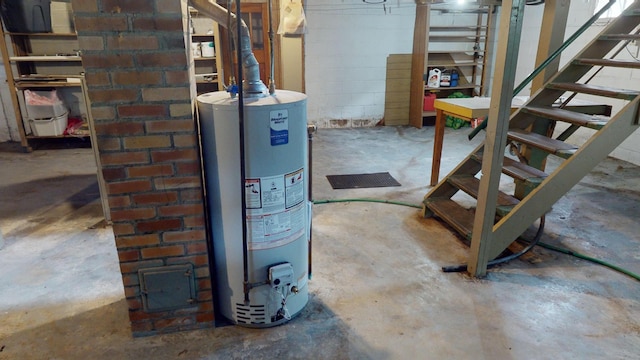 unfinished basement featuring water heater and stairway
