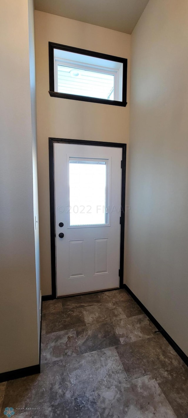 doorway to outside featuring stone finish flooring, baseboards, and plenty of natural light