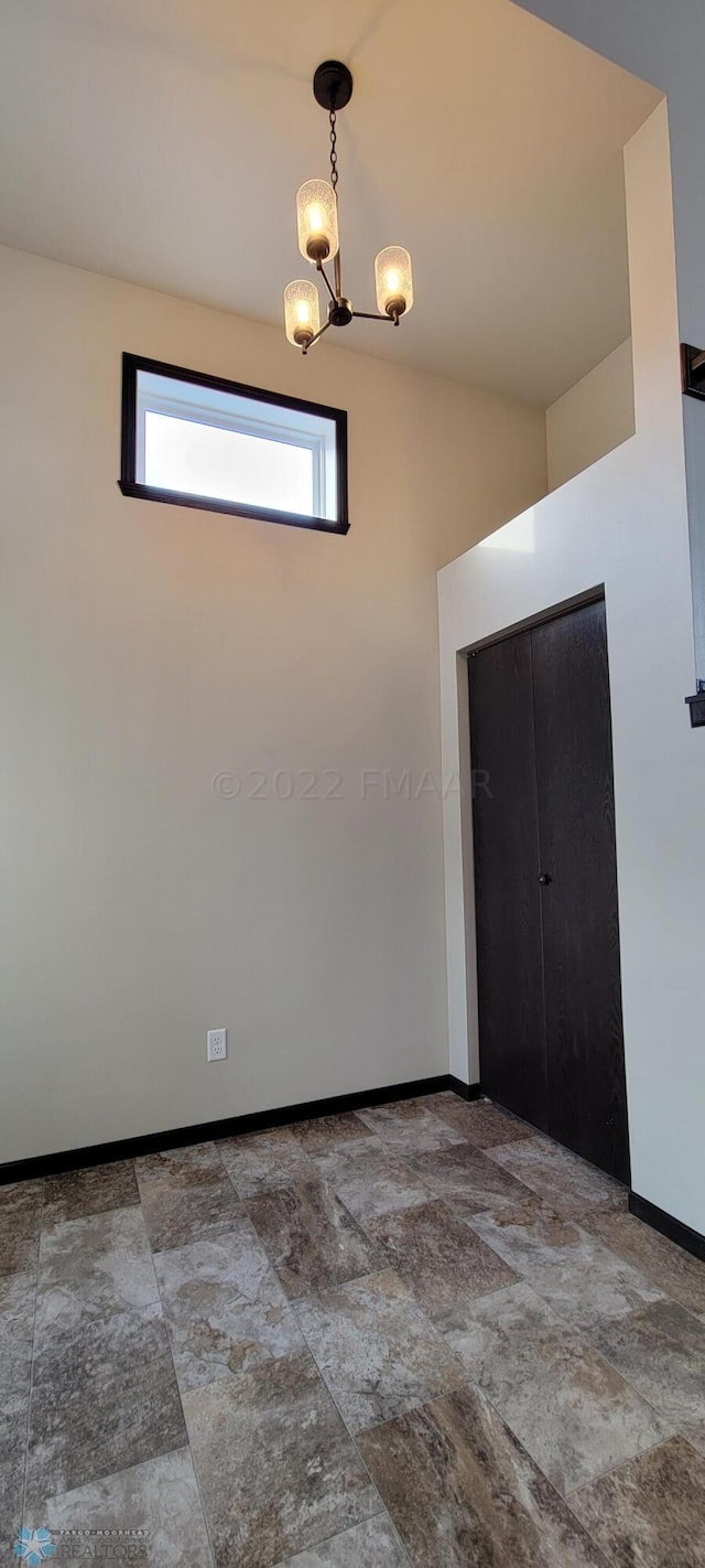 interior space featuring a chandelier, baseboards, and stone finish floor
