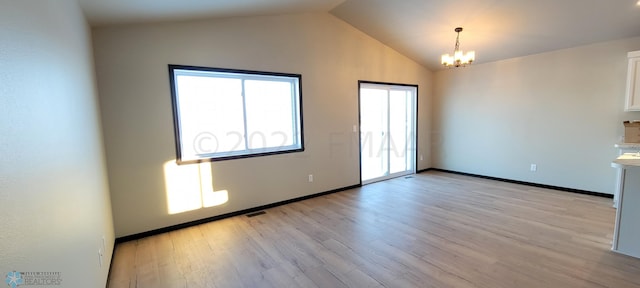 unfurnished room with an inviting chandelier, light wood-style flooring, vaulted ceiling, baseboards, and visible vents