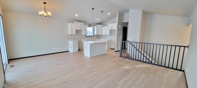 kitchen with a notable chandelier, light wood-style flooring, vaulted ceiling, a kitchen island, and white cabinets